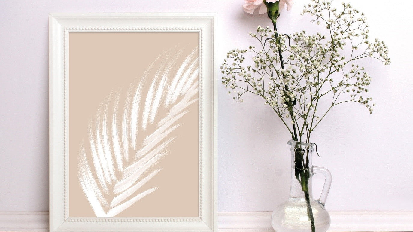 White Leaf in Photo Frame Against Wall with Flowers in Vase
