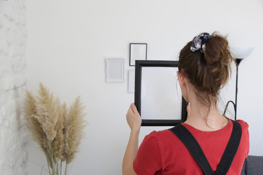 Woman Holding Black Photo Frame Against Wall
