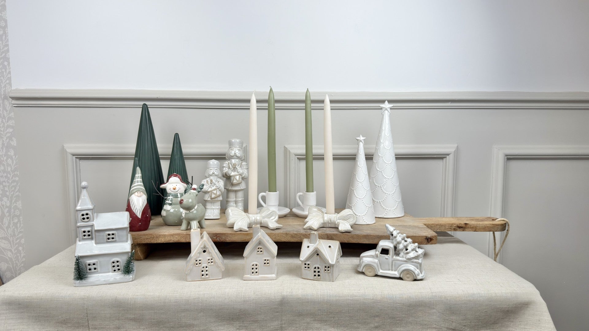 Decorative items including small houses, a car, and festive figures on a table with a neutral background.